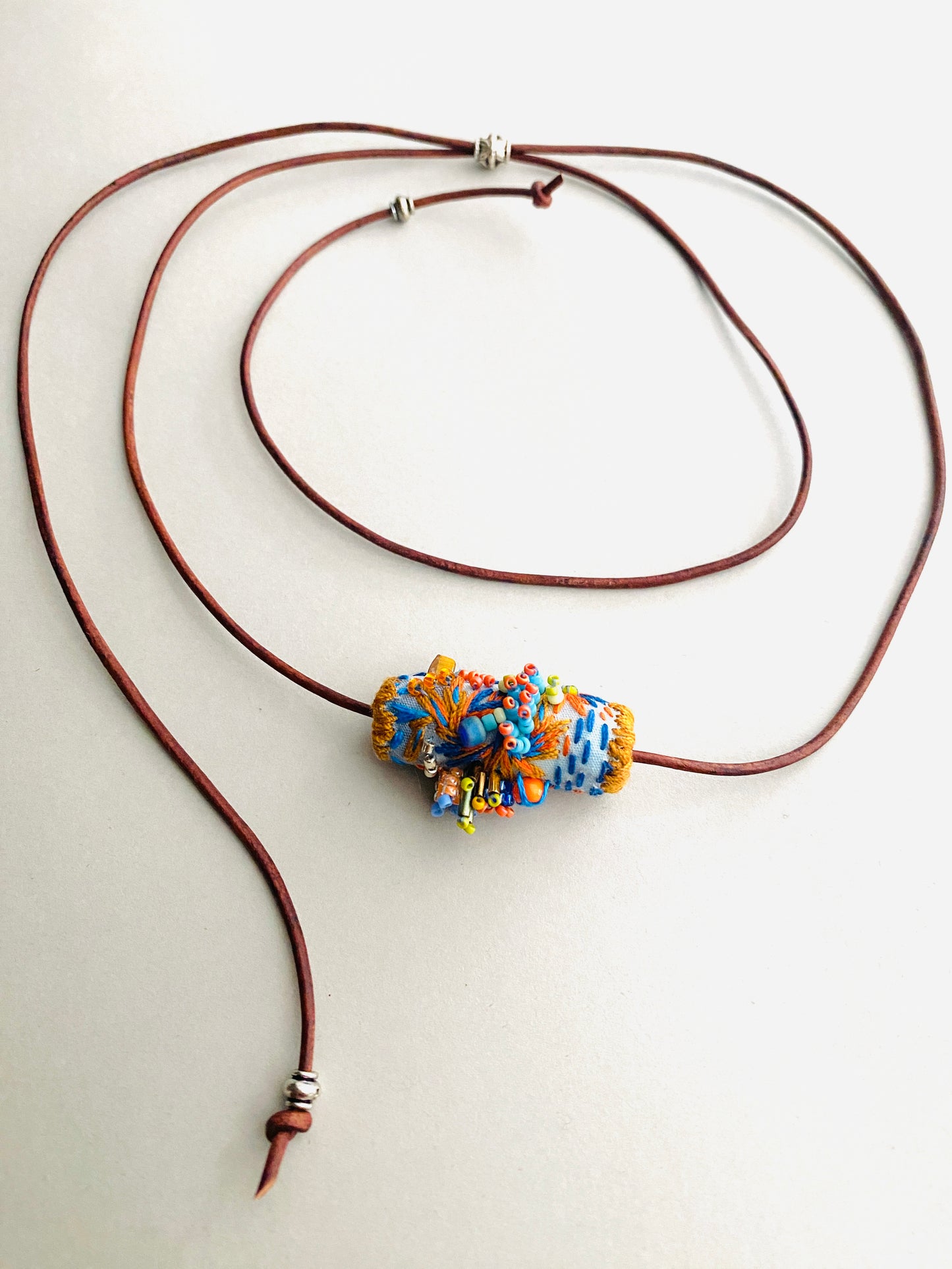 "Horizon" Blue and orange embroidered and beaded textile necklace.